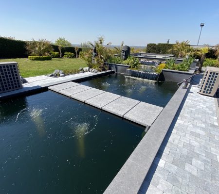 Moderne koi-vijver met beluchting en waterval om koi van extra zuurstof te voorzien bij warm weer