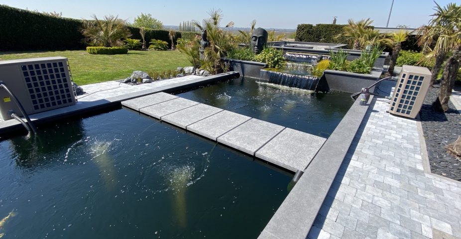 Moderne koi-vijver met beluchting en waterval om koi van extra zuurstof te voorzien bij warm weer