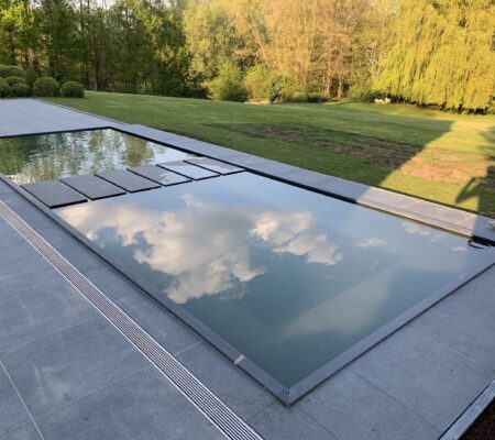 Moderne, strak aangelegde koivijver met blauwe hardstenen rand en stapstenen, geïntegreerd in een terras.